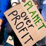 picture of someone holding the sign 'planet over profit'