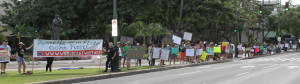 King Kalakaua statue overlooks climate activists as they wave signs before the Waikiki Climate March, Honolulu, USA
