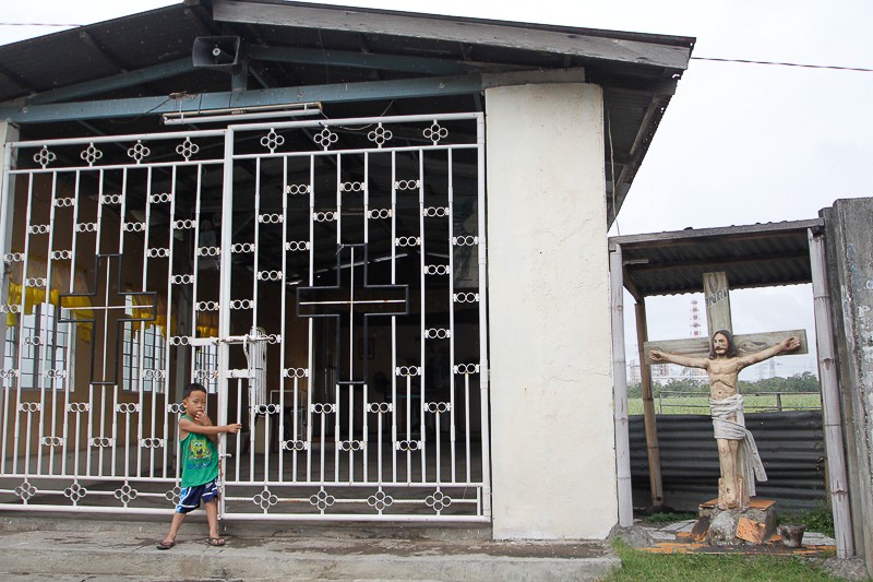 A child plays in front of a chapel that stands along the route to Barangay Quisumbing, Calaca, Batangas. © AC Dimatatac