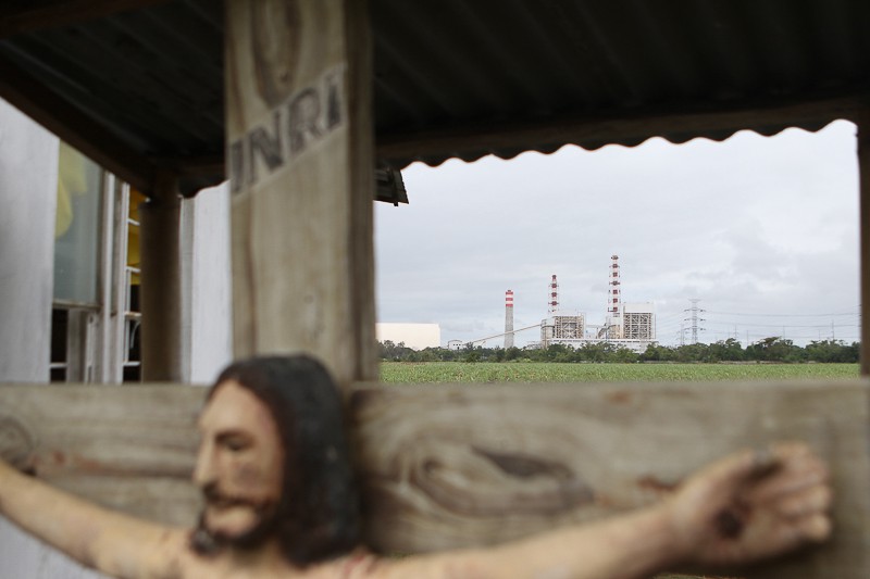 The coal plant stands prominently behind the statue of a crucified Christ at a chapel near Barangay Quisumbing, Batangas. © AC Dimatatac
