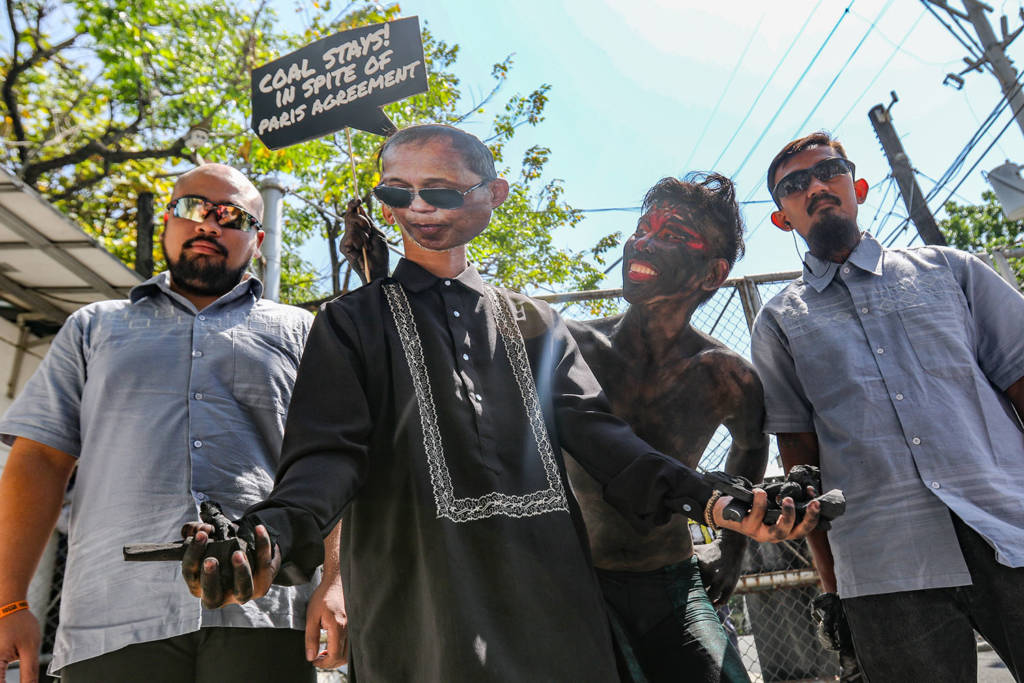 An activist dressed as a 'coal demon' shows how the coal industry influences Energy Secretary Cusi, at a protest action held at the Department of Energy , in Taguig Metro Manila.