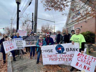 Protestors hold signs reading "Boycott Chase Bank," "Chase Bank Climate Change Profiteer," and others.