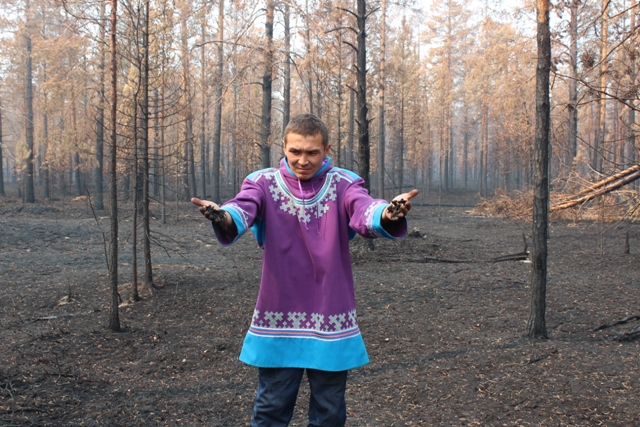 Александр Айпин держит в руках ягель, сгоревший во время лесных пожаров